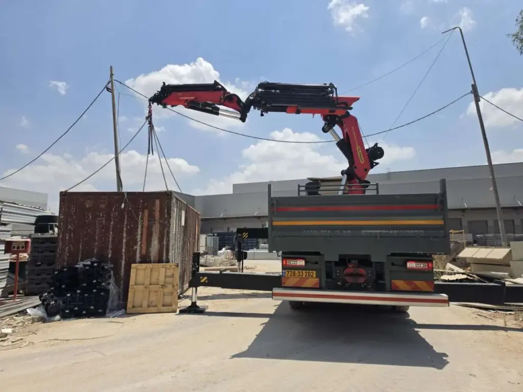 מנוף פורק מטען ממשאית בחזית מבנה תעשייה