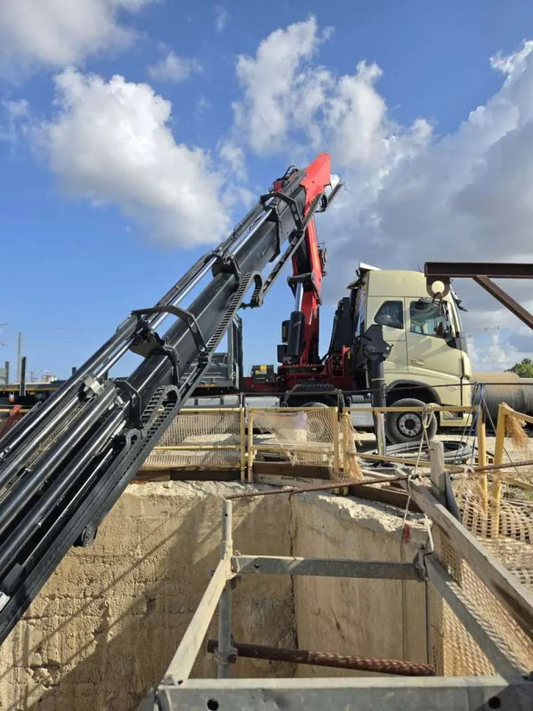 מנוף מרים ציוד מעל בור חפירה באתר בנייה