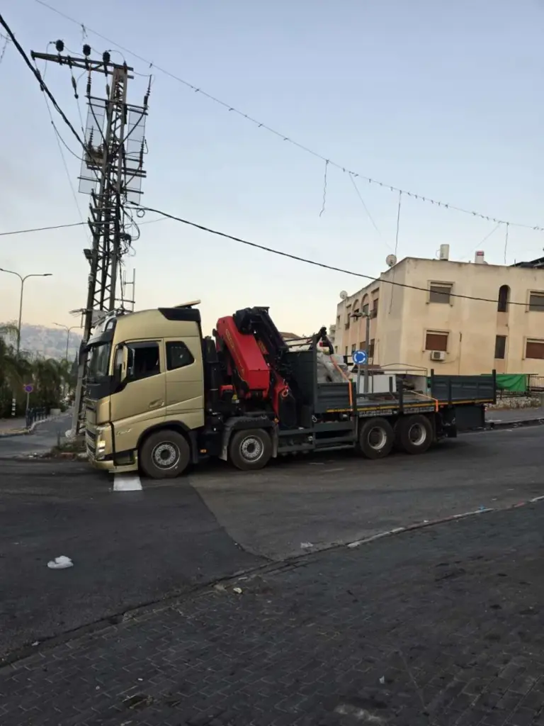 משאית מנוף של עווד מנופים נוסעת ברחוב ביישוב