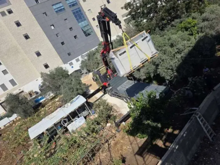 מנוף מציב יחידה טרומית ליד בניין מגורים